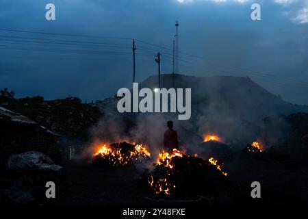 Dhanbad, Jharkhand, Indien. 31. August 2024. In einem Tagebau am Stadtrand von Dhanbad wird ein Kohlehaufen verbrannt. In Jharia im indischen Bundesstaat Jharkhand leben rund 600.000 Menschen. Es liegt im Herzen des größten Kohlefeldes der Nation. Jharia, das seinen Namen von der Stadt und Region mit dem gleichen Namen erhält, ist auch bekannt für eine schreckliche Rate von Kohleflözbränden, die eine der Hauptquellen der Umweltverschmutzung in der Region und weltweit sind. Kohlendioxid wird durch Kohlebrände in massiver Menge in die Atmosphäre abgegeben. (Bild: © Amarjeet Kumar S Stockfoto