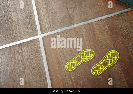 Nahaufnahme eines Holzbodens mit gelben Schuhabdrücken und sich kreuzenden silbernen Linien Stockfoto