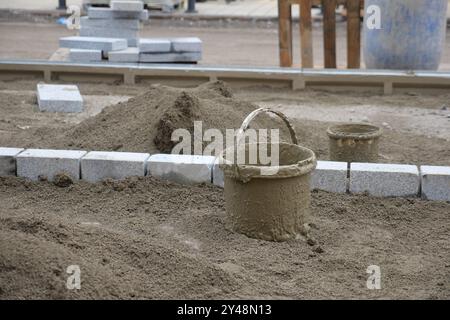 Eine geschäftige Baustelle mit Eimern und Ziegeln auf einem sandigen Untergrund Stockfoto