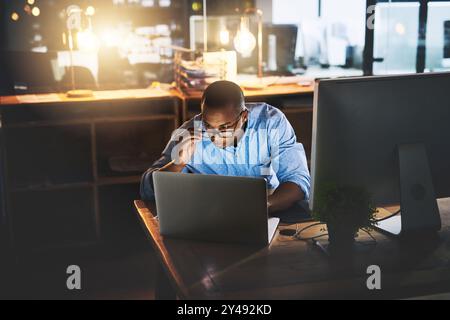 Afrikaner, Geschäftsmann und Technologie für die nächtliche Forschung als Spezialist für Unternehmenskommunikation. Männlicher Mann, der spät arbeitet und mit dem Computer arbeitet Stockfoto