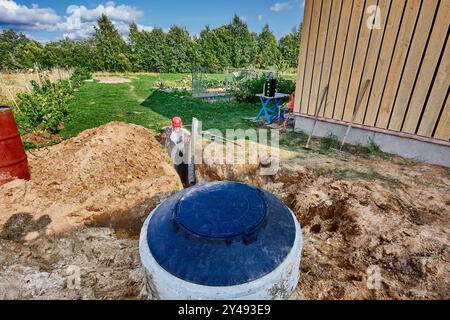 Verlegung von Drainagegewebe und Lochrohr in einem Absorptionsgraben für Abwasserleitungen. Stockfoto