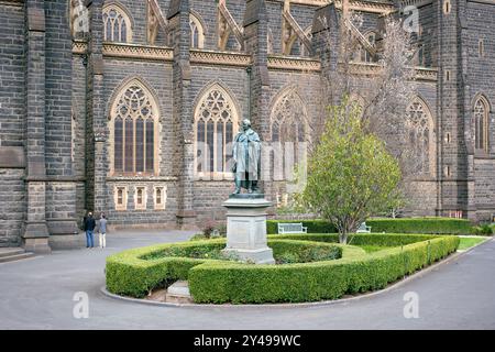 Statue des irischen Patrioten Daniel O'Connell vor der St. Patrick's Cathedral in Melbourne und zwei Männer, die auf die Kathedrale in Victoria, Australien blicken. Stockfoto