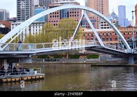 Menschen, die an einem regnerischen Tag den Yarra River auf der Evan Walker Bridge zwischen Melbourne CBD und Southbank überqueren, Melbourne, Victoria, Australien. Stockfoto