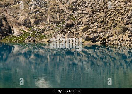 Klarer Bergsee mit felsigem Ufer und alpiner Landschaft Stockfoto