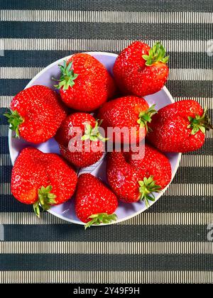 Erdbeeren auf einem Teller. Erdbeeren in einem runden Teller auf dem Tisch. Reife und süße Erdbeeren auf einem Teller. Stockfoto