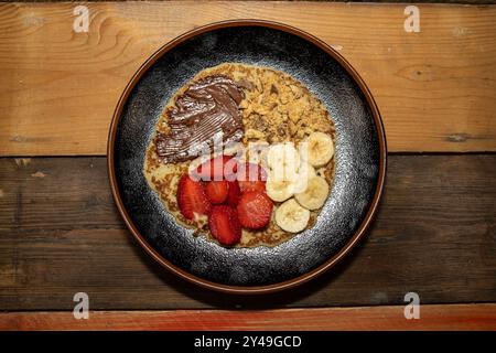 Ein köstlicher Pfannkuchen mit Erdbeeren, Bananen und Schokolade auf einem hölzernen Küchentisch Stockfoto