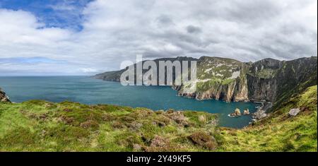 Ein Panoramablick auf die Klippen der Slieve League in Irland, die die gesamte Küste und die Bucht darunter mit lebhaftem Grün und blauem Wasser zeigen Stockfoto