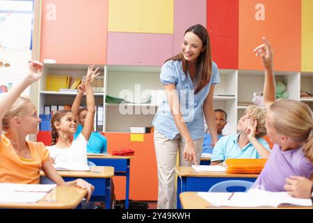 Frau, Frage und Kinder mit in der Schule erhobenen Händen für Erziehung, Diskussion und Antwort. Glücklich, Lehrer und Schüler mit Geste Stockfoto