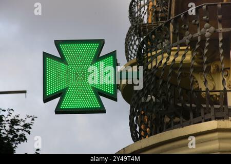 Beleuchtetes grünes Apotheken-Kreuzschild mit LED-Lichtern. Barcelona, Katalonien, Spanien. Stockfoto