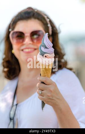 Lateinamerikanische Frau, die während der Sommersaison eine Eiskugel hält. Stockfoto