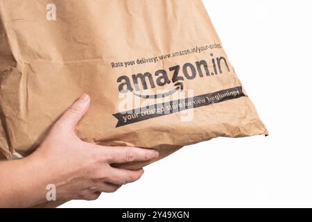 Paketpaket mit Eigenlieferung von Amazon Indien. Amazon.in Etikett Verpackungsbeutel isoliert auf weißem Hintergrund. Weibliche Hände erhalten einen Amazon bo Stockfoto