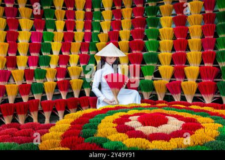 Asiatische Frau, die ein ao dai Kleid mit Räucherstäbchen trägt, trocknet in Hue, Vietnam. Stockfoto