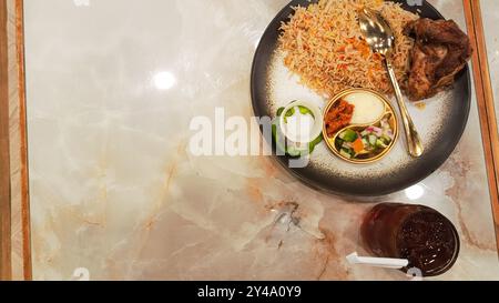 Kebuli-Reis (nasi Kebuli) und Eistee, typisch arabisches Essen hergestellt in Indonesien auf einem Tisch mit leerem Platz daneben, Winkel flach gelegt Stockfoto