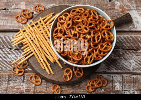 Leckere Brezelkracker und salzige Sticks auf Holztisch, flach gelegen Stockfoto