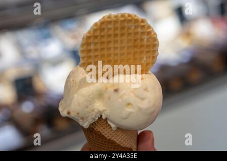 Hand hält Schokoladeneiskegel nahe oben isoliert. Stockfoto