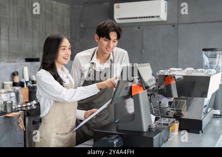Junge Barista arbeiten an einem modernen Coffee Shop-Schalter mit Touchscreen-Registrierung zusammen Stockfoto