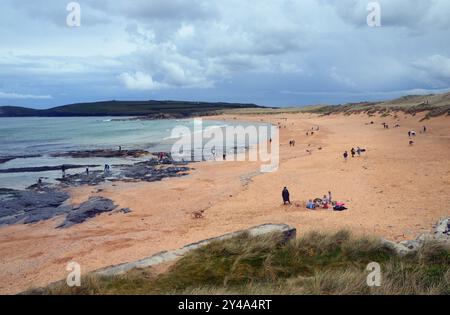 Menschen, die am Strand von Booby's/Constantine Bay auf dem Southwest Coastal Path in North Cornwall, England, Großbritannien spazieren gehen. Stockfoto