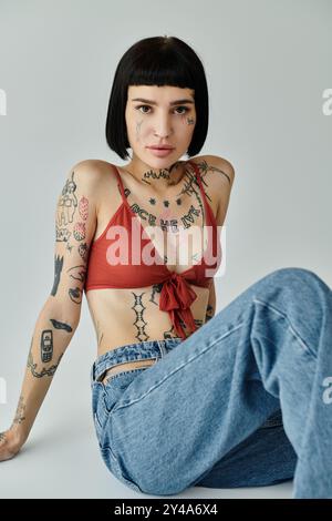 Eine stilvolle Frau zeigt ihre Tattoos, während sie anmutig sitzt. Stockfoto