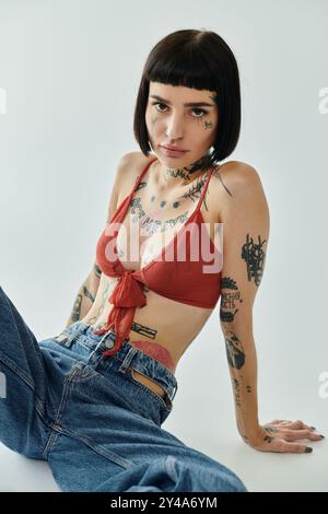 Eine modische junge Frau zeigt ihre Tattoos in einer kreativen Pose. Stockfoto