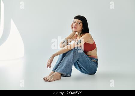 Eine junge Frau posiert elegant und zeigt ihre Tattoos und ihr stilvolles Outfit. Stockfoto