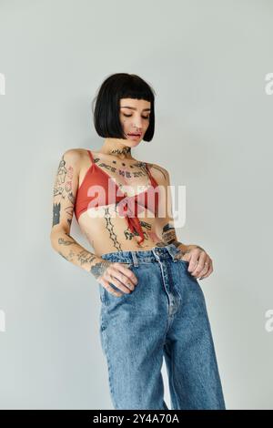 Eine stilvolle Frau zeigt selbstbewusst ihre einzigartigen Tattoos, während sie elegant posiert. Stockfoto