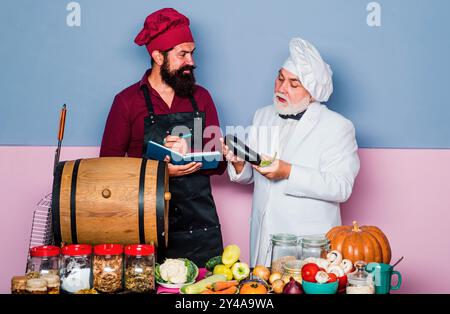 Zwei lächelnde Köche, Köche oder Bäcker. Bärtiger Koch, der in der Küche des Restaurants steht. Rezept kochen. Stockfoto