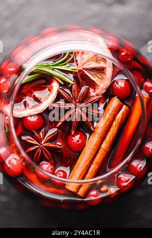 Blick von oben auf Glühwein im Glas mit Orangenscheiben, Zimtstangen, Sternanis, Rosmarin und Preiselbeeren aus nächster Nähe. Lebensmittelfotografie Stockfoto