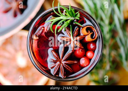 Roter Glühwein im Glas mit Zimtstangen, Sternanis, Rosmarin und Preiselbeeren aus nächster Nähe. Lebensmittelfotografie Stockfoto