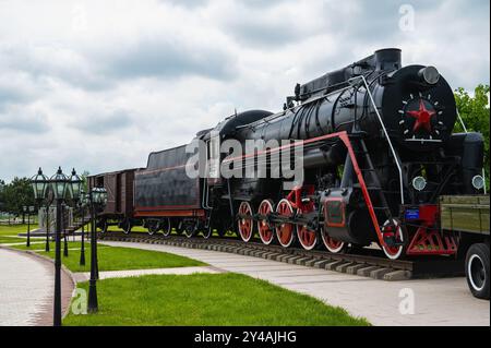 Nazran, Inguschetien, RUSSLAND - 12. MAI 2024: Gedenkstätte für Erinnerung und Ruhm. Große Personendampflokomotive auf der Hauptstrecke. Klassischer Eisenbahnverkehr. Transpo Stockfoto