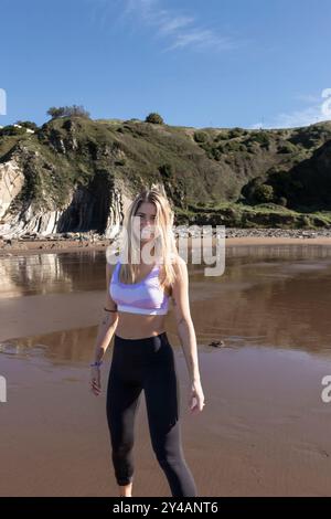 Frau in Aktivkleidung, die einen sonnigen Tag am Strand genießt Stockfoto