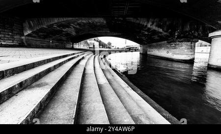 Besucher schlendern entlang der geschwungenen Stufen an der seine unter der Jenaer Brücke in Paris und genießen die ruhige Atmosphäre und die architektonische Schönheit der Umgebung. Stockfoto