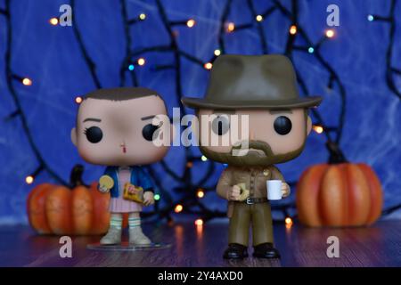 Funko Pop Actionfiguren von Jim Hopper und Eleven aus der TV-Serie Stranger Things. Blauer Nebel, Spinnennetz, bunte Lichter, Halloween Kürbisse. Stockfoto