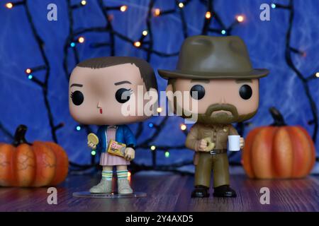 Funko Pop Actionfiguren von Jim Hopper und Eleven aus der TV-Serie Stranger Things. Blauer Nebel, Spinnennetz, bunte Lichter, Halloween Kürbisse. Stockfoto