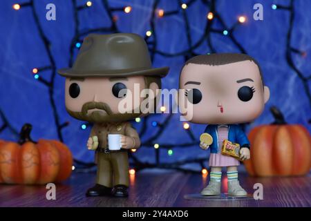 Funko Pop Actionfiguren von Jim Hopper und Eleven aus der TV-Serie Stranger Things. Blauer Nebel, Spinnennetz, bunte Lichter, Halloween Kürbisse. Stockfoto