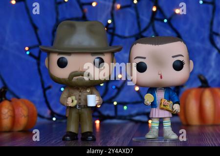 Funko Pop Actionfiguren von Jim Hopper und Eleven aus der TV-Serie Stranger Things. Blauer Nebel, Spinnennetz, bunte Lichter, Halloween Kürbisse. Stockfoto