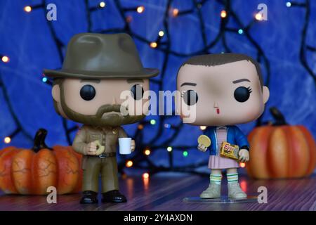 Funko Pop Actionfiguren von Jim Hopper und Eleven aus der TV-Serie Stranger Things. Blauer Nebel, Spinnennetz, bunte Lichter, Halloween Kürbisse. Stockfoto