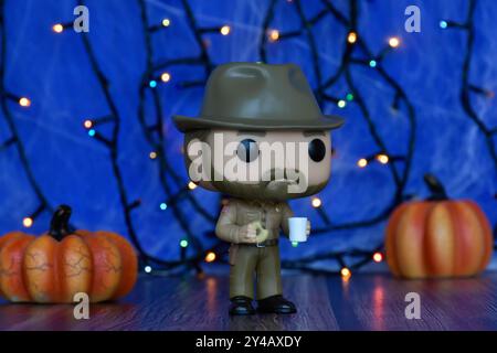 Funko Pop Actionfigur von Jim Hopper aus der beliebten Horror-TV-Serie Stranger Things. Blauer Nebel, Spinnennetz, bunte Lichter, Halloween Kürbisse. Stockfoto