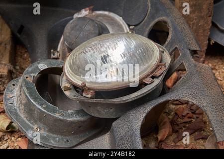 Alte, entsorgte Autoscheinwerfer und andere Ersatzteile in Schrottplatz-Nahsicht, beschädigte veraltete oder nicht mehr funktionsfähige Fahrzeugteile im Außenbereich Stockfoto