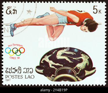 LAOS - UM 1987: Eine in Laos gedruckte Briefmarke von den Olympischen Spielen in Seoul. Sport und griechische Töpferausgabe zeigt Hochspringen und Schüssel mit Griffen Stockfoto