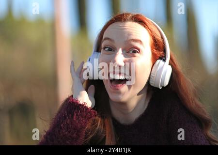 Mädchen hört Musik mit ihren Kopfhörern und macht freundliche und fröhliche Gesten Stockfoto