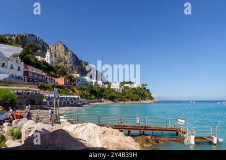 Malerischer Blick auf die Küste und farbenfrohe Gebäude vor dem Hintergrund der Klippen in Capri, Italien, mit klarem blauem Himmel und türkisfarbenem Wasser Stockfoto