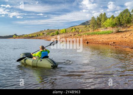 Senior männlich paddelt mit einem aufblasbaren Packboot am Horsetooth Reservoir in Colorado Stockfoto