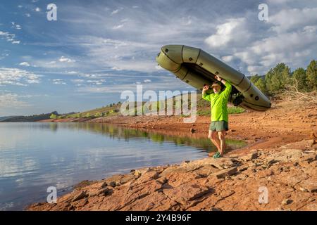 Senior männlicher Paddler startet ein aufblasbares Packboot an einem Ufer des Horsetooth Reservoir in Colorado Stockfoto