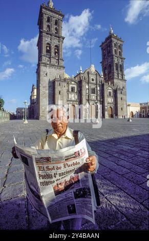 Mexiko, Puebla. Man liest die Zeitung El sol de Puebla auf dem Platz Zocalo vor der Kathedrale. Stockfoto