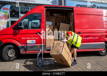 Ein Mitarbeiter von Parcelforce entlädt ein großes Paket aus seinem Transporter im Stadtzentrum von Truro in Cornwall, Großbritannien. Stockfoto