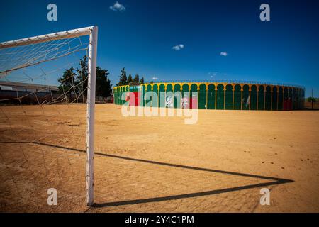 Ein einzigartiger Blick auf eine tragbare Stierkampfarena in Aznalcazar, Sevilla, Spanien, mit einem Fußballtor im Vordergrund unter einem klaren blauen Himmel. Stockfoto