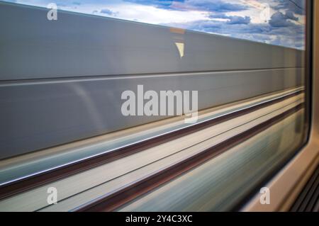 Panoramablick durch ein Zugfenster, das die dynamische Bewegung des AVE-Hochgeschwindigkeitszugs auf der Fahrt durch Cordoba in Andalusien, Spanien, festnimmt. Erfahrung Stockfoto
