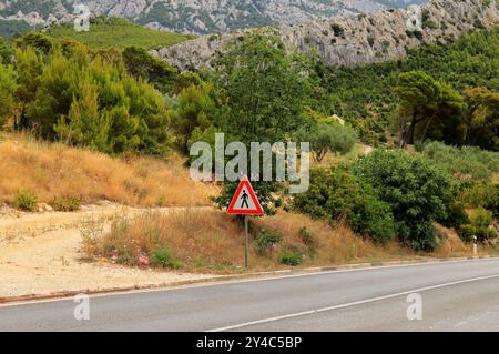 Straßenschild Fußgängerüberquerung auf einer Bergstraße in Kroatien. Dreieckiges Warnschild für Fußgänger, um die Straße sicher zu überqueren. Geben Sie Fußgänger Frei Stockfoto