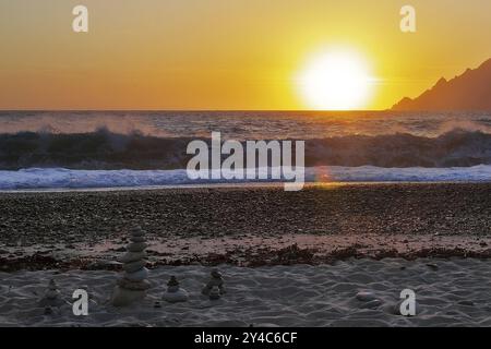 Landkunst vor den Surfwellen bei Sonnenuntergang am Strand von Porto, Korsika Stockfoto