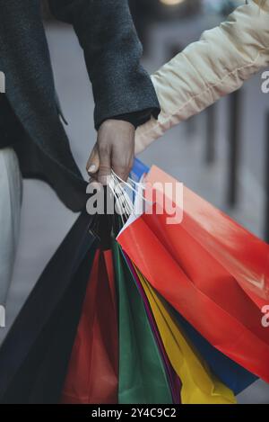 Bunte Papiertüten in den Händen eines Paares. Einkaufs- und Verkaufskonzept Stockfoto